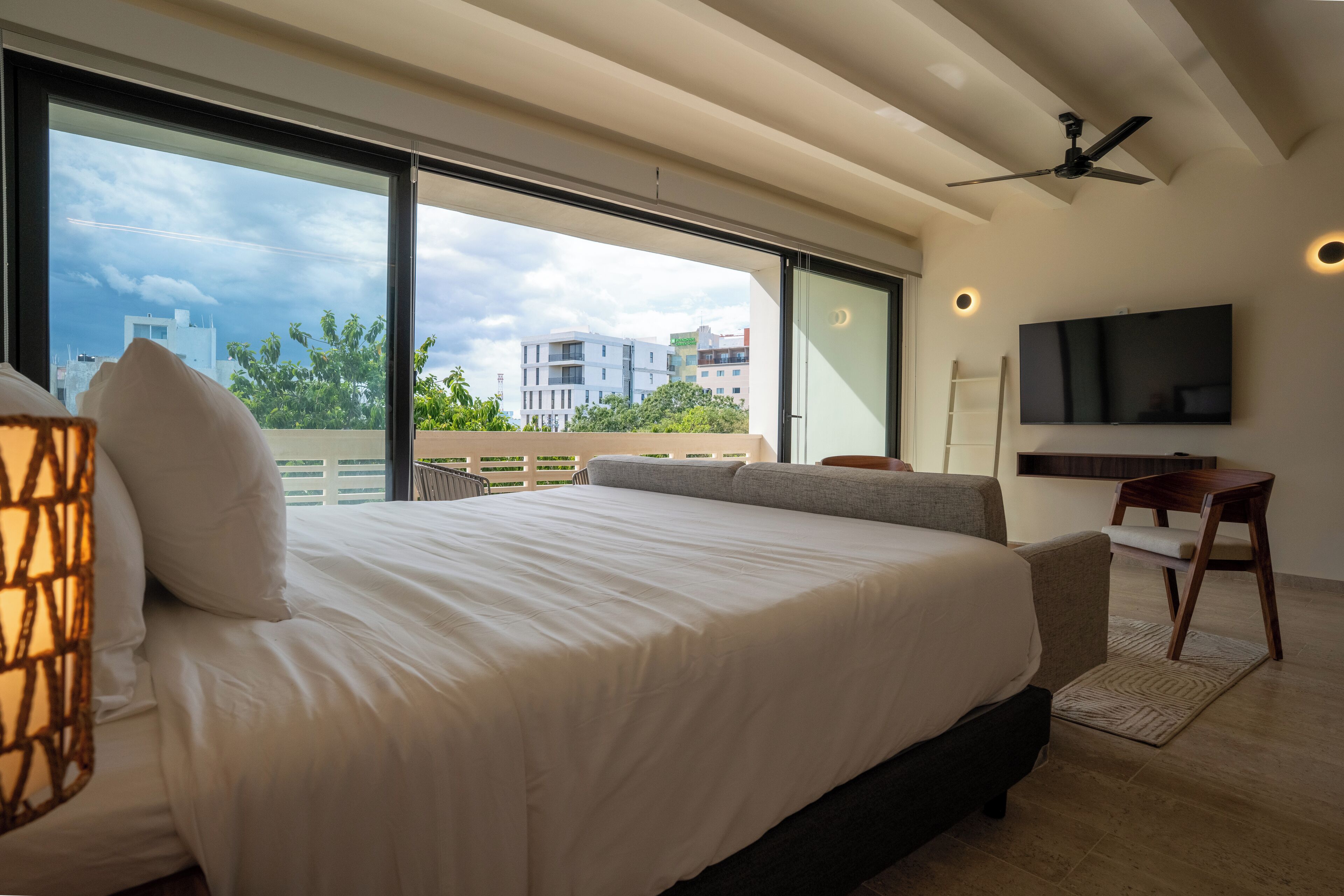 A modern bedroom with a large bed, a desk, and a TV.