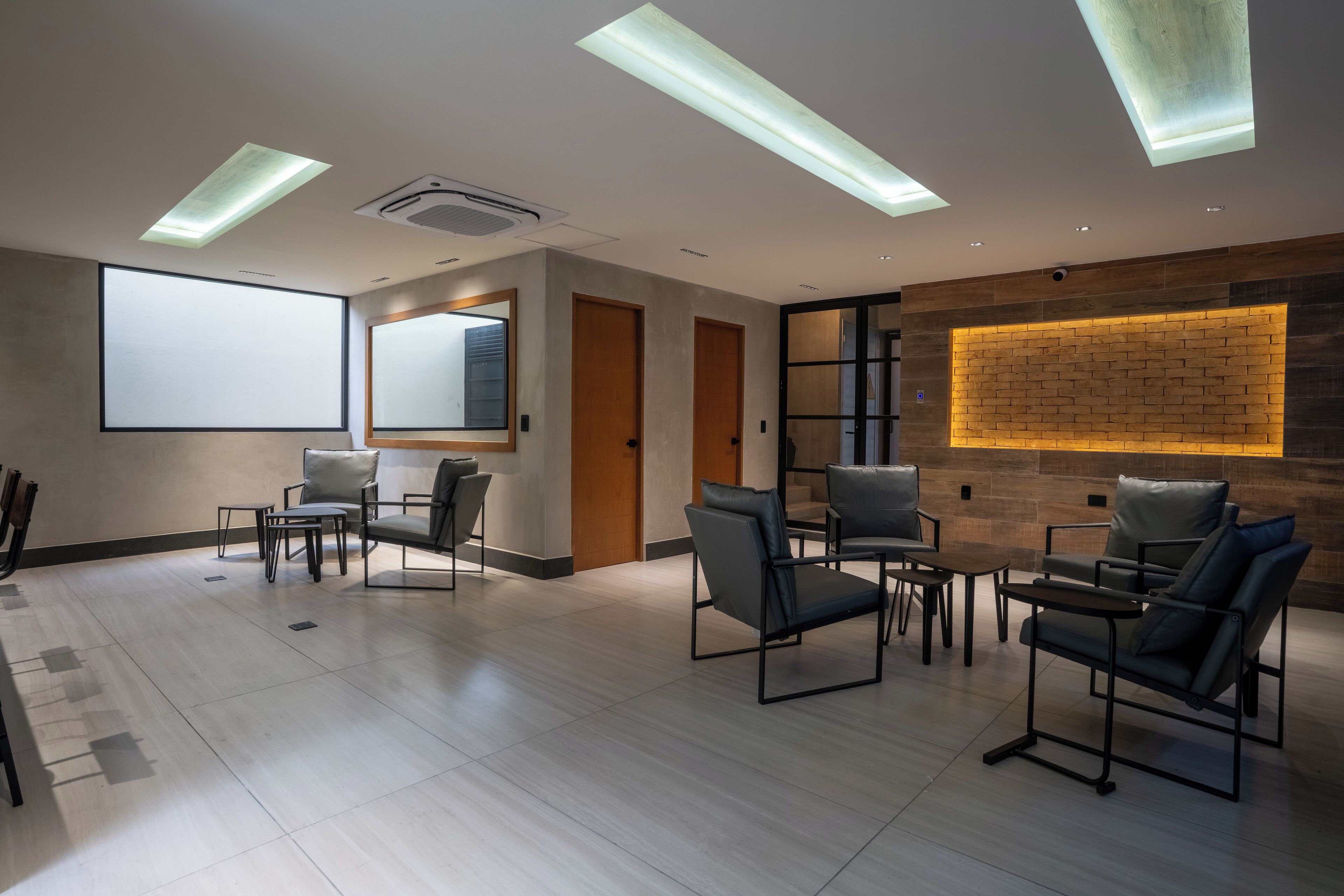 A modern conference room with a large projection screen, multiple seating areas, and a brick accent wall.