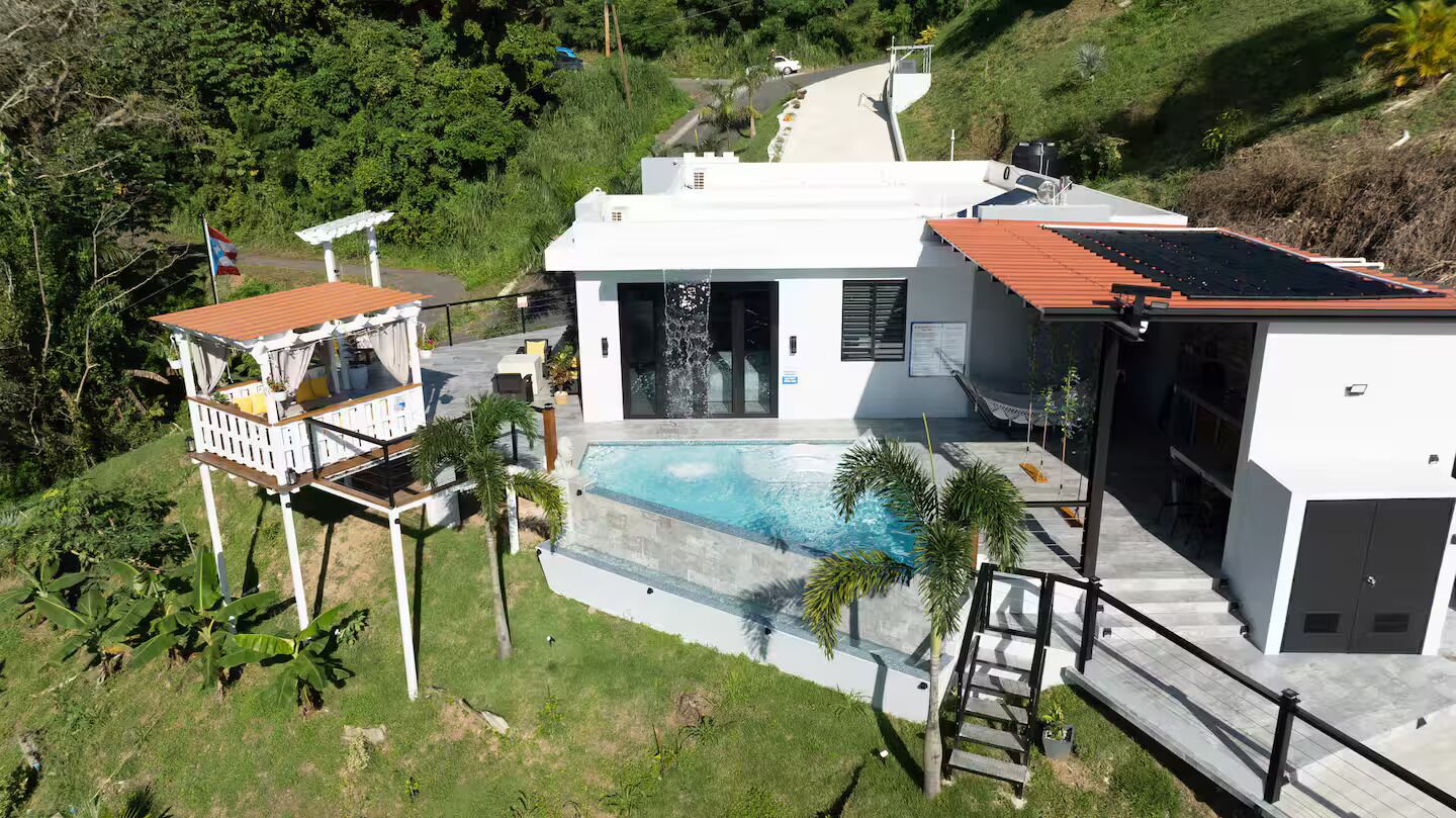 Une maison moderne dotée d’une piscine, de panneaux solaires et d’une petite terrasse.