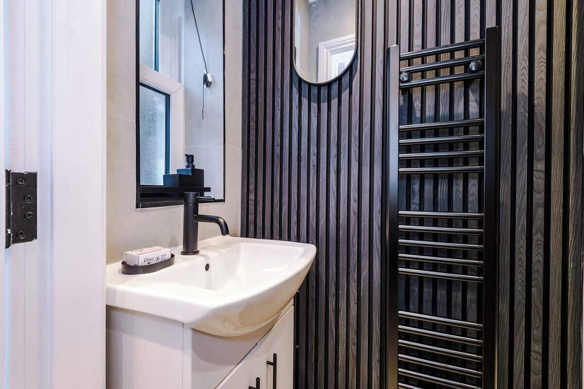 Une salle de bain avec un lavabo blanc, un miroir et un porte-serviettes.