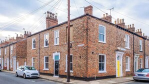 A row of terraced houses with brick facades, white window frames, and a street in front. - Stylish 1-Bed Flat | York Centre | Sleeps 4 (York)