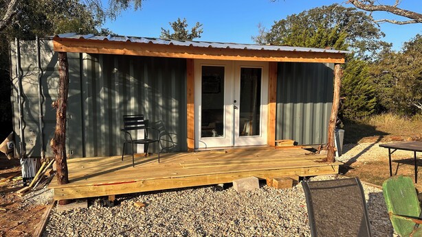 A small cabin with a wooden deck, a door, and a window. - Tiny Tiger Shipping container with AC in charming Whitney (Whitney)