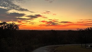 A sunset view with a dirt path leading to a grassy area with a bench and a lamp post. - Tiny Tiger Shipping container with AC in charming Whitney (Whitney)