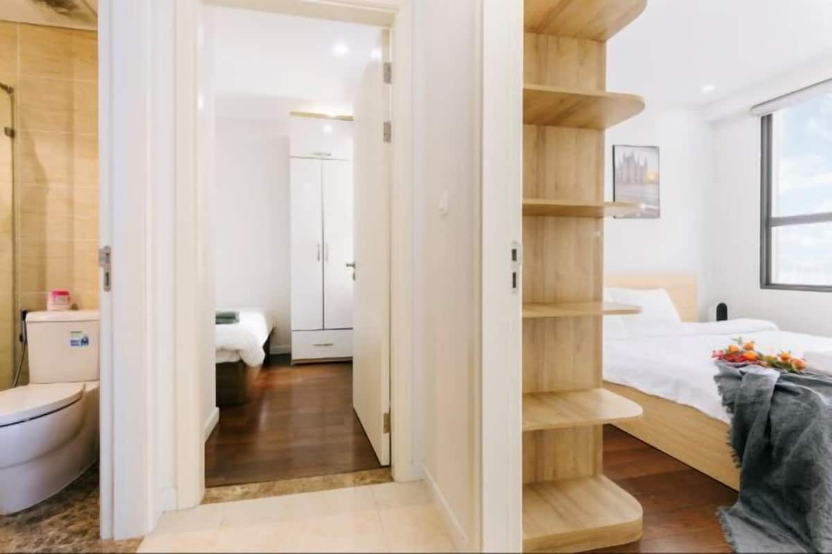 Ein modernes Hotelzimmer mit einem Holzbett, einem weißen Kleiderschrank und einem Badezimmer mit Toilette und Waschbecken.