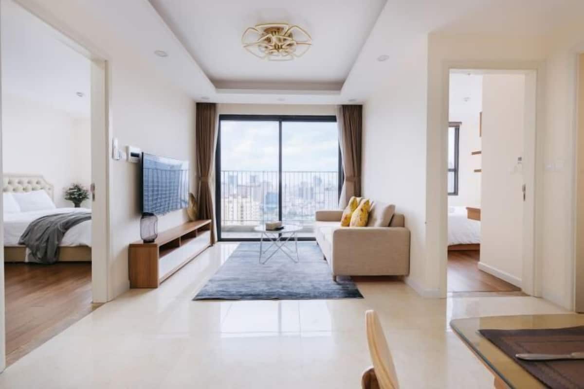 Ein modernes Hotelzimmer mit Bett, Sofa, Fernseher und Balkon mit Blick auf die Stadt.
