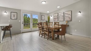 A dining area with a wooden table and chairs, a bar stool, and a view through glass doors to a balcony. - Family-Friendly Mtn Retreat |Fireplace•Pets•Trails (Florissant)