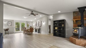 A spacious living area with hardwood flooring, a dining table with chairs, a fireplace, and a ceiling fan. - Family-Friendly Mtn Retreat |Fireplace•Pets•Trails (Florissant)
