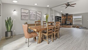 A spacious dining area with a wooden table and chairs, a potted plant, and a fireplace in the background. - Family-Friendly Mtn Retreat |Fireplace•Pets•Trails (Florissant)