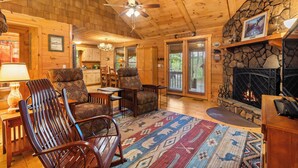 Un intérieur de chalet chaleureux avec une cheminée, des meubles en bois et un mur d’accent en pierre.
