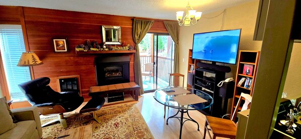 Un salon avec une cheminée, un téléviseur, un canapé, une table basse et une bibliothèque.
