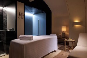 Un dormitorio con cama, mesita de noche, lámpara y zona de estar.