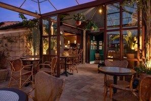 Een binnenplaats met rieten meubilair, een bar en potplanten.
