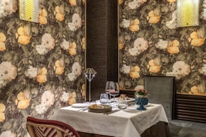 A dining area with a table set for two, a wine glass, and a lamp. - TB Place Roma (Rome)