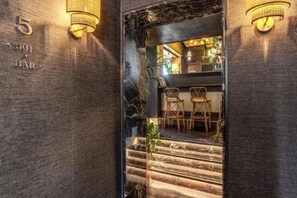 A bar area with a staircase leading to a seating area, a number '501' sign, and wall-mounted lighting fixtures. - TB Place Roma (Rome)