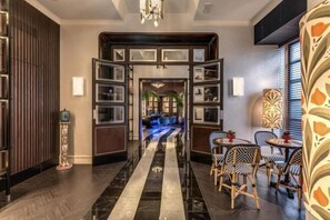 Um saguão de hotel com corredor central, área de estar e vista para uma sala de jantar.