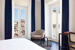Une chambre d’hôtel avec un lit, une chaise, une petite table et une vue sur l’extérieur, visible à travers une porte.