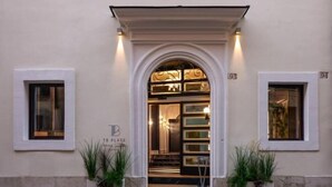 A building entrance with a white archway, two potted plants, and a sign with the letters "TB". - TB Place Roma (Rome)