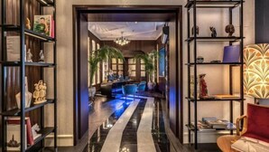 A hotel lobby with a black and white striped floor, a reception desk, and a seating area with blue chairs. - TB Place Roma (Rome)