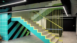 A modern staircase with geometric patterns and a neon-lit handrail. - Funker Hostel (Málaga)