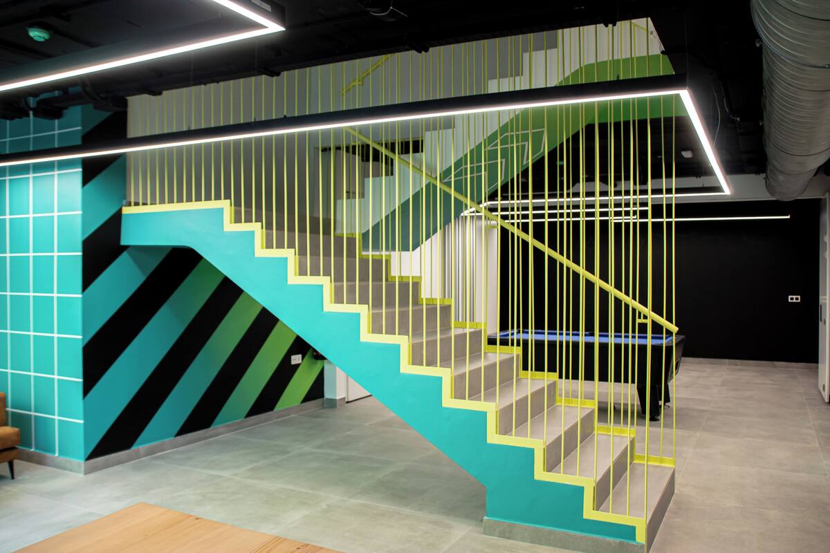 A modern staircase with geometric patterns and a neon-lit handrail.