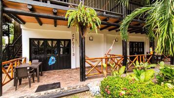 Un patio con mobiliario exterior, una planta colgante y un jardín bien cuidado.