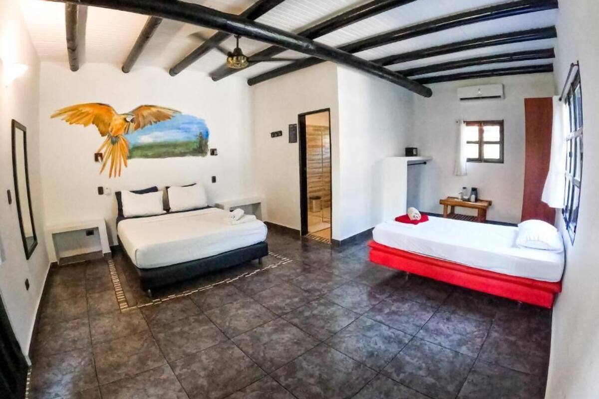 A room with two beds, a mural of a bird, and a tiled floor.
