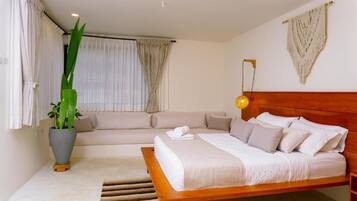 A bedroom with a wooden bed, a sofa, a potted plant, and a wall-mounted lamp.