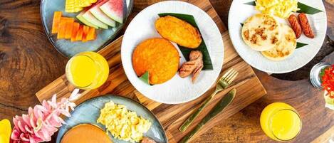 A breakfast spread with various dishes on plates, including pancakes, scrambled eggs, and fresh fruit.