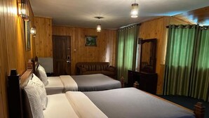 A room with two beds, wooden walls, a mirror, and a green curtain. - Jaithra Inn (Nuwara Eliya)