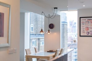 A modern dining area with a large window, pendant lights, and a framed picture on the wall.