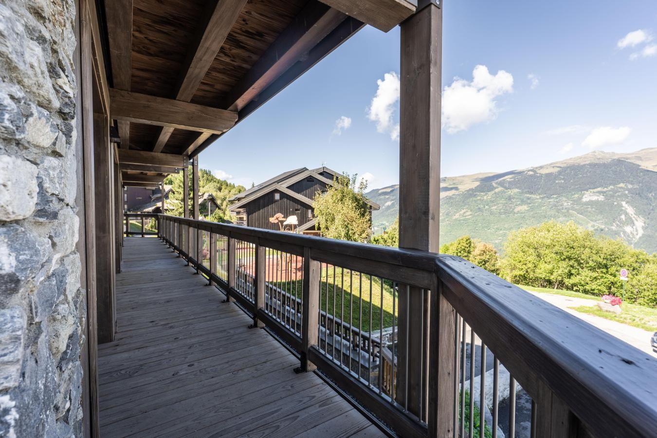 A wooden balcony with a railing overlooking a mountainous landscape.
