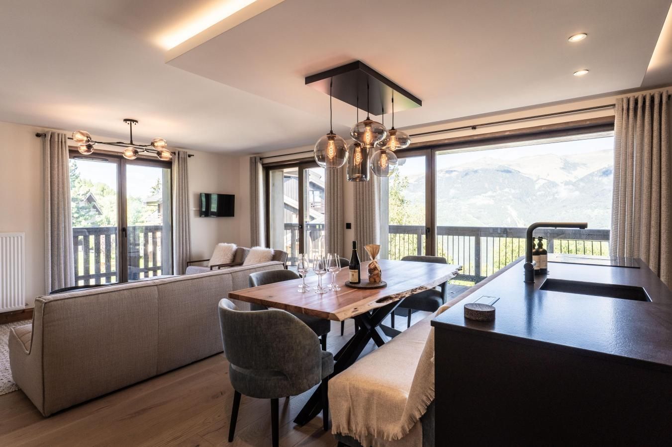 A modern dining area with a wooden table, chairs, and a built-in kitchen island with a sink.
