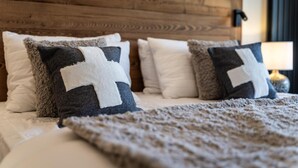 Een bed met een houten hoofdbord, meerdere kussens en een dekbed.
