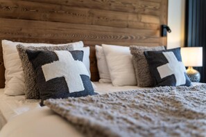 A bed with a wooden headboard, multiple pillows, and a blanket. - 100m from ski slopes, Ground floor, view open/resort/mountain, balcony, parking, tv, ski locker (La Plagne)