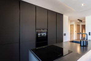 Une cuisine moderne avec un plan de travail noir, un four encastré et un robinet élégant.