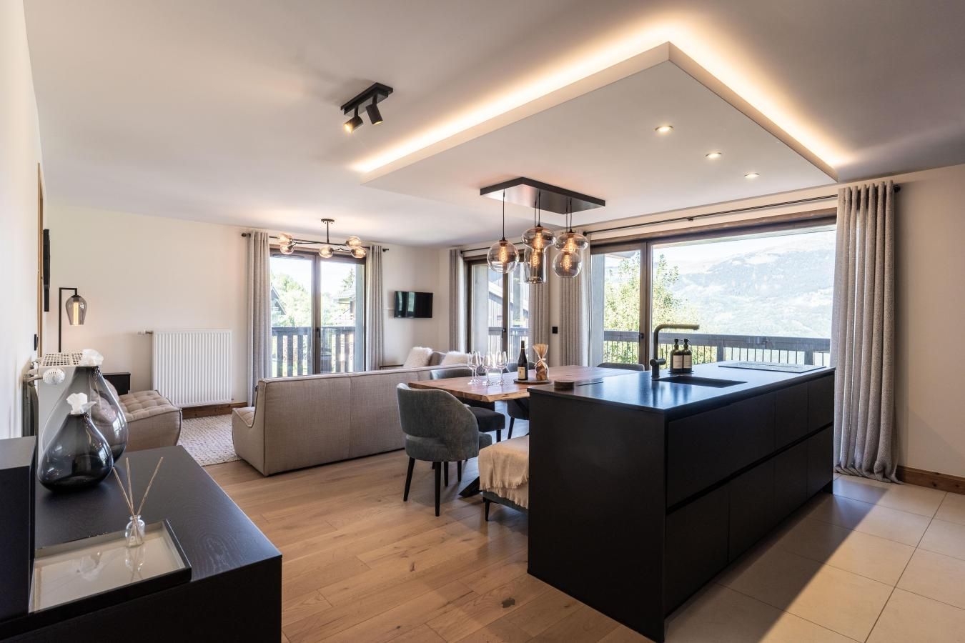 Una cucina moderna con isola centrale, zona pranzo con divano e ampie finestre che offrono vista sull'esterno.