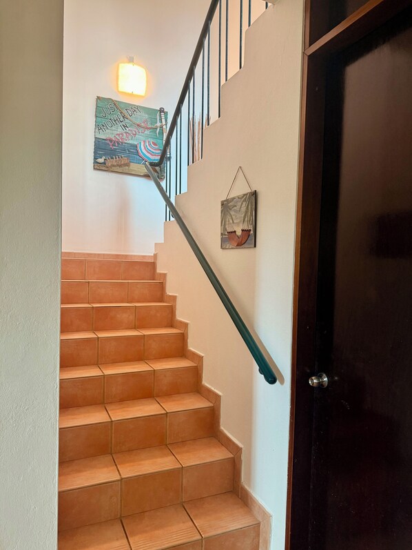 Un escalier avec une rampe, une applique murale et une porte.