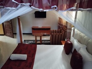 A bedroom with a bed, a desk, a chair, and a TV. - Villa Martis Hotel Kakamega (Kakamega)