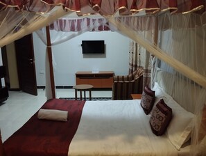 A bedroom with a canopy bed, a television on the wall, a desk, and a chair. - Villa Martis Hotel Kakamega (Kakamega)