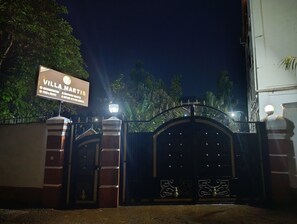 A Villa Martinez éjszakai, kerítéssel körbevett bejárata, melyen egy tábla található.