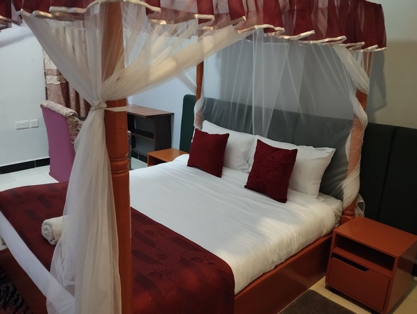 A four-poster bed with a canopy, two bedside tables, and a nightstand.