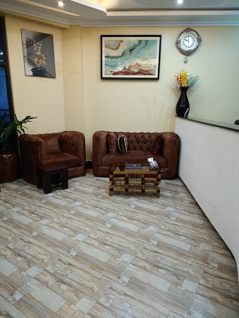 Una sala de estar con dos sofás marrones, una mesita de centro de madera y una planta en maceta.