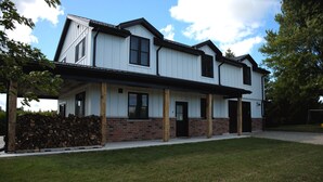 Ein zweistöckiges Haus mit einer überdachten Veranda, einem Backsteinfundament und einem Holzstoß.