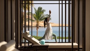 A person practicing yoga in a room with a view of the sea and palm trees. - Jumeirah Muscat Bay (Bandar Jissah)