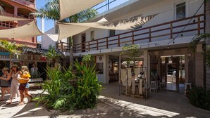 Un patio con una zona de estar a la sombra, una fuente y diversas plantas.