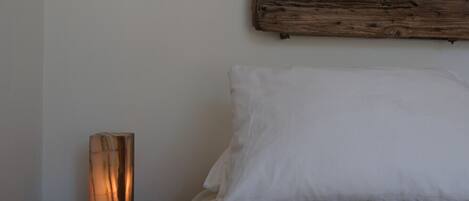 Ein Schlafzimmer mit einem hölzernen Kopfteil, einem Nachttisch und einem weißen Kissen.
