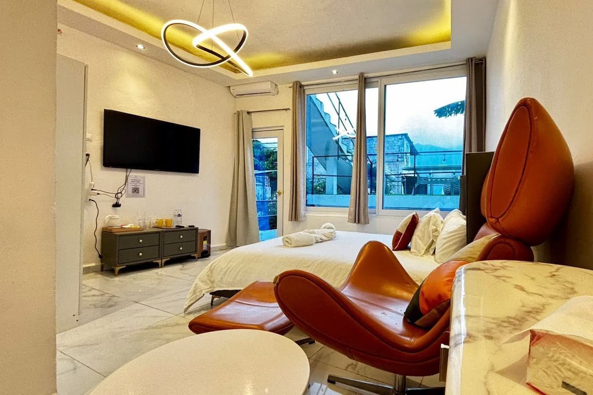 A modern hotel room with a bed, a desk, a chair, and a TV.