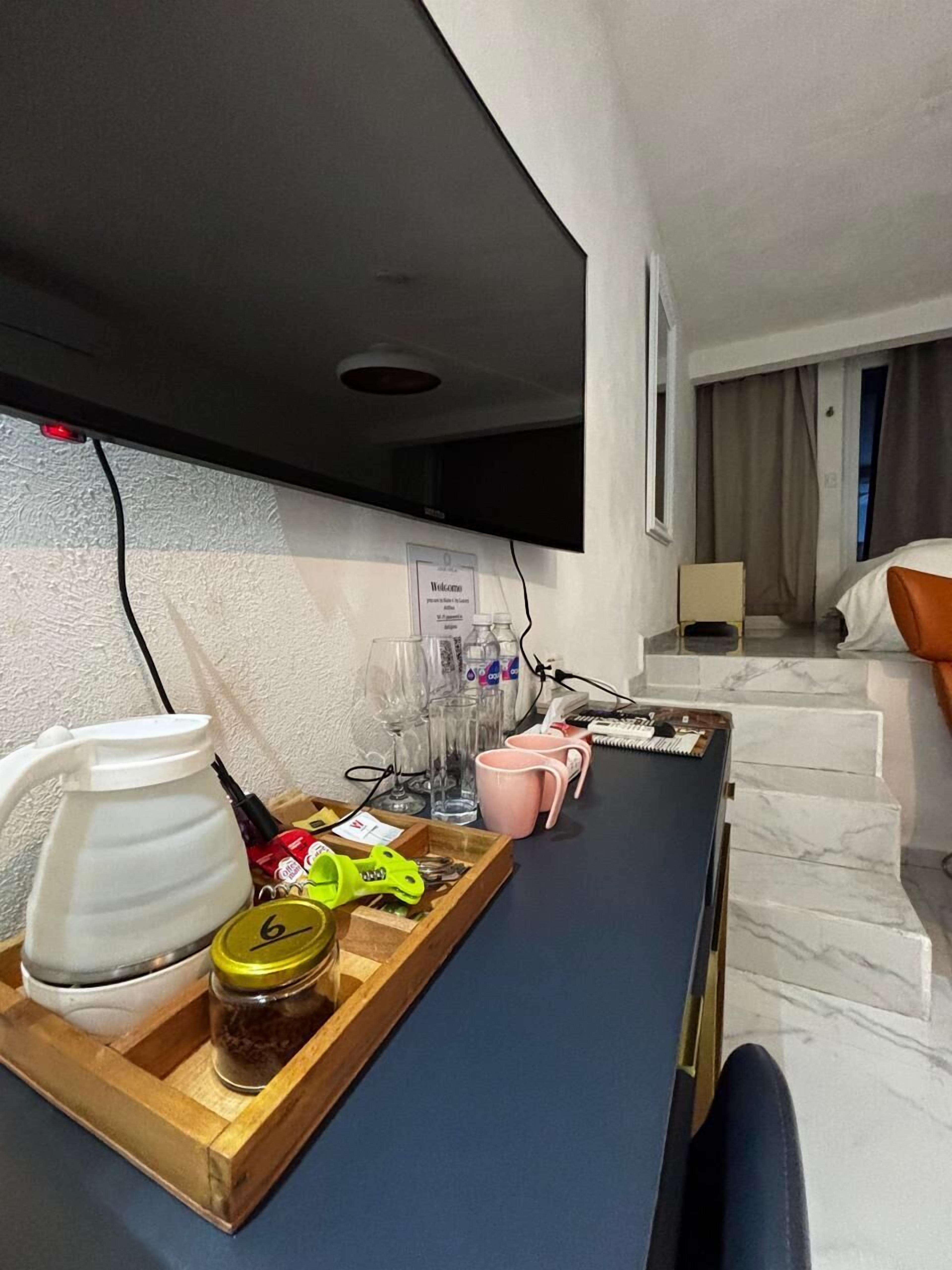 A hotel room with a desk, a TV, a bed, and a bathroom.
