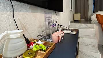 A hotel room with a desk, a TV, a bed, and a bathroom.