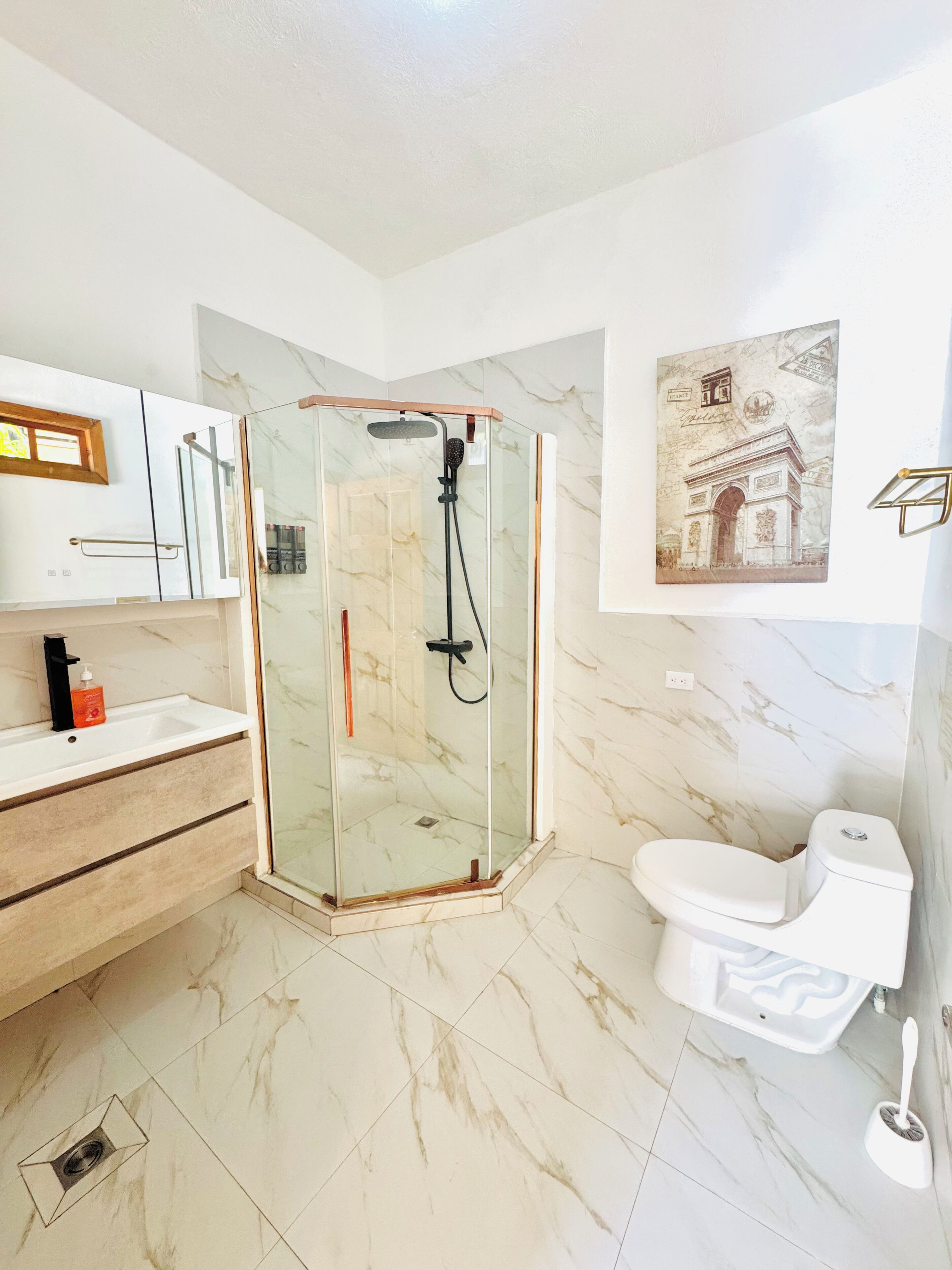 A modern bathroom with a glass-enclosed shower, a white toilet, and marble flooring.